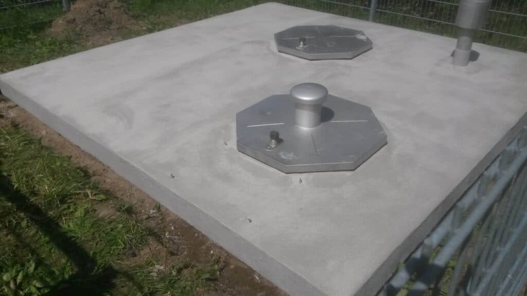 Neu beschichtete Fläche mit zwei achteckigen Metallabdeckungen und Rohrdurchführungen.