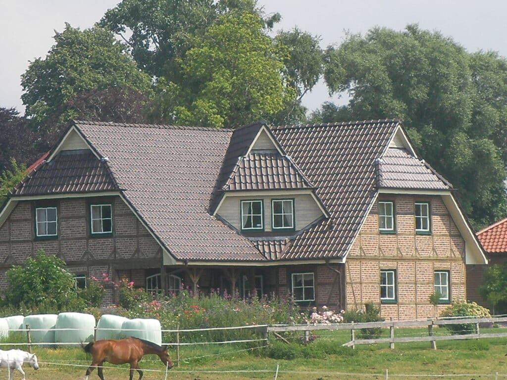 Braun gedecktes Dach mit mehreren Giebeln und Dachfenstern auf einem Holzhaus.