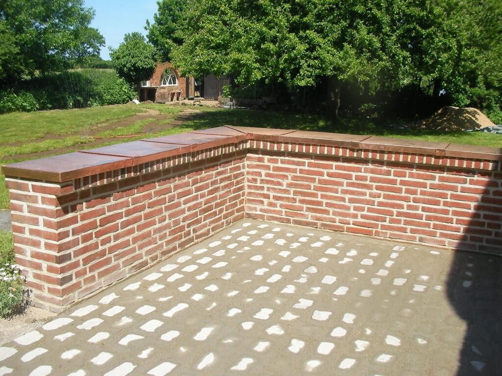 Niedrige Backsteinmauer um eine Terrasse mit kupferfarbener Metallabdeckung.
