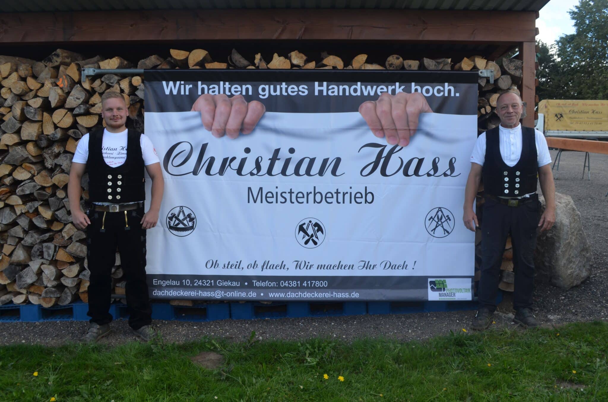 Dennis und Christian Hass stehen neben dem neuen Bauzaunbanner.